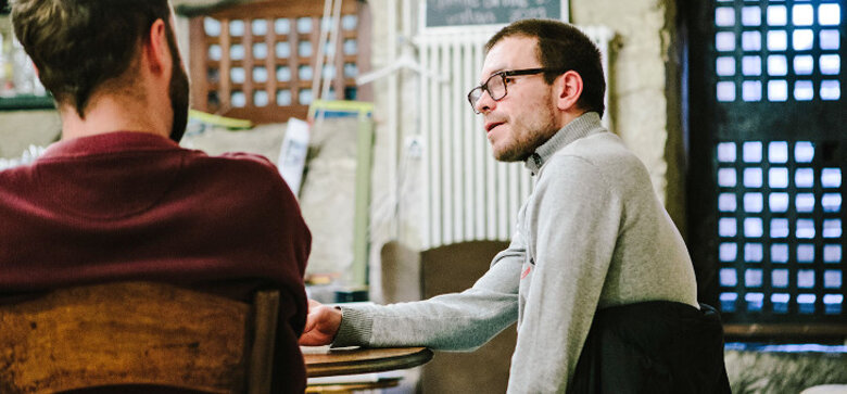 Un homme avec des lunettes parle à une autre personne